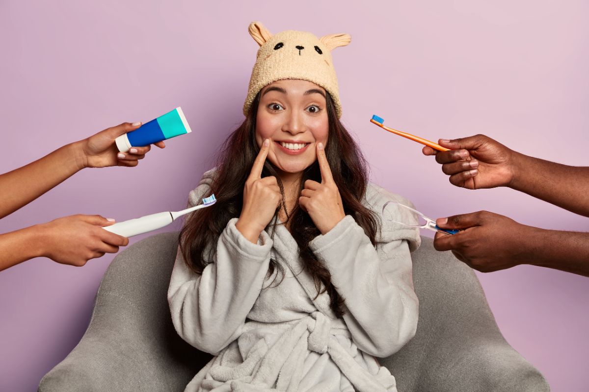 Woman smiling while surrounded by toothbrushes and toothpaste, highlighting daily dental care habits.