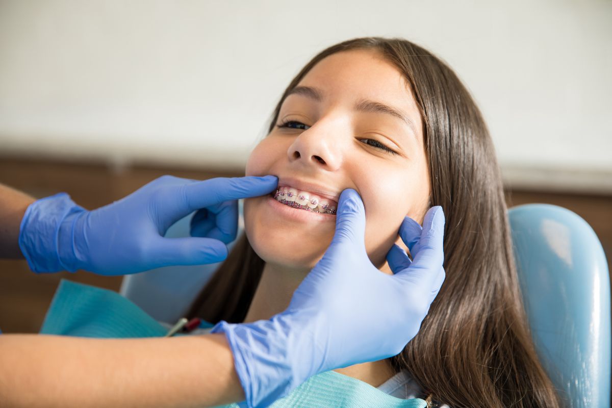 Orthodontist adjusting braces on a teenage patient’s teeth.