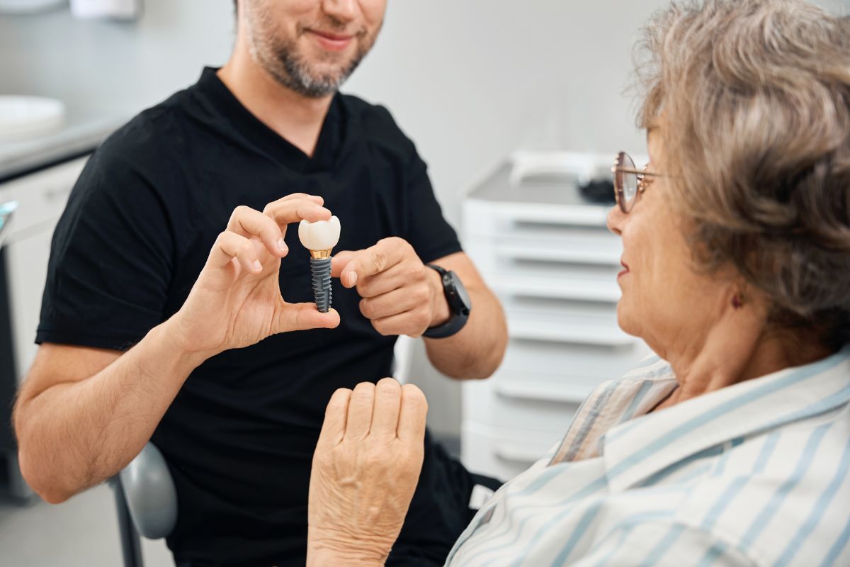 dental implants Dentist explaining dental implant model to a patient.